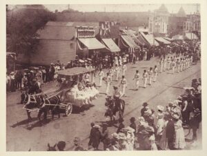 horse-drawn wagon full of girls in white dresses rolling down University Avenue